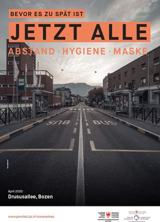 Das Schwarz-Weiß-Foto vom April 2020 zeigt die Drususallee, eine der Hauptverkehrsadern in Bozen, völlig leer. Das Bild wird von dem Slogan begleitet: Jetzt alle. Abstand, Hygiene, Maske. 